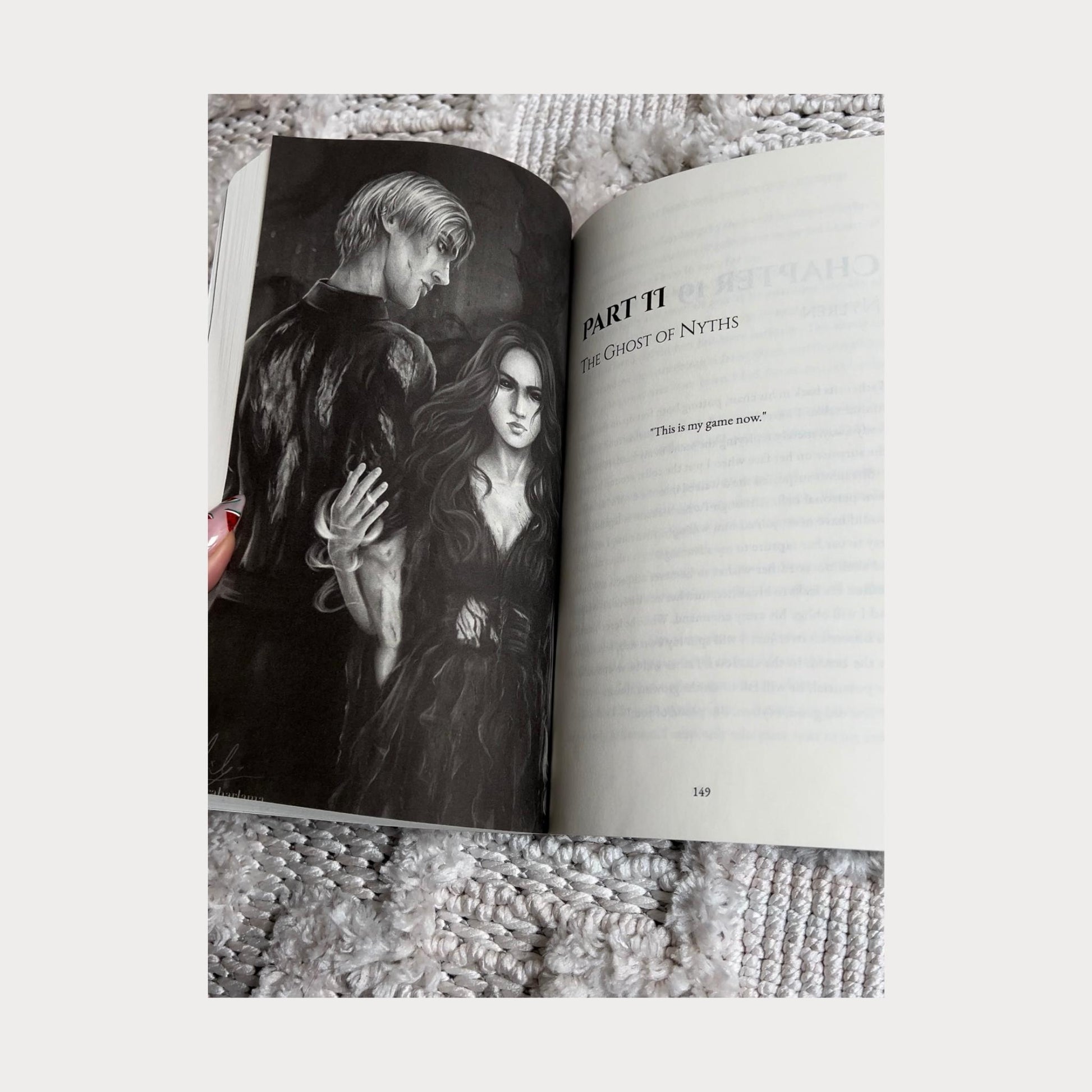 A reader holding an open copy of Daughter of Darkness Prince of Bloodshed by Allie Cole, showing a black and white character illustration on the left page featuring a dark-haired woman and a pale-haired man standing together in an intense scene. The right page displays the title Part II The Ghost of Nyths along with the quote This is my game now