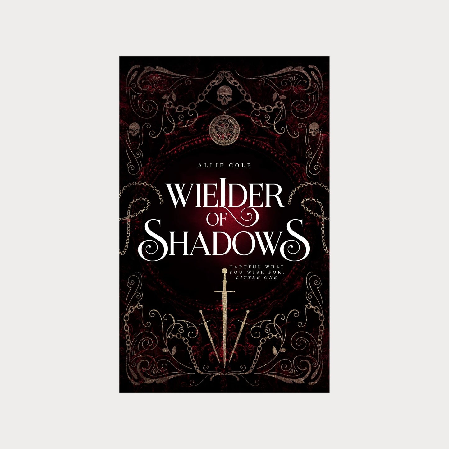 Hardcover edition of Wielder of Shadows by Allie Cole, a dark fantasy romance novel. The cover features gothic filigree, chains, skulls, and a glowing red background, with a silver sword at the center. The tagline reads Careful what you wish for, little one